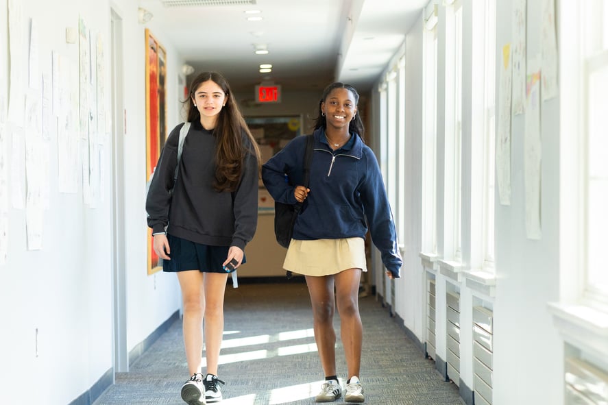 Two girls walk through hallway of Upper School