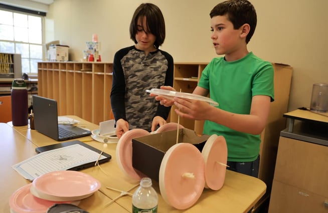 Two boys designing car with wheels