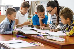 A kind female teacher spends time with her elementary school students