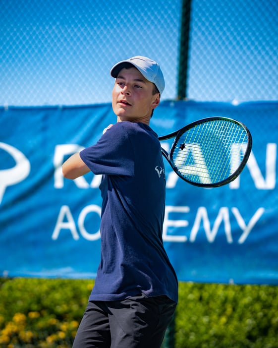 Boy swinging tennis racket over his shoulder