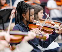 Girl playing violin in music class