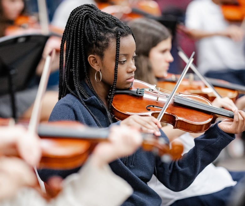 Girl playing violin in music class