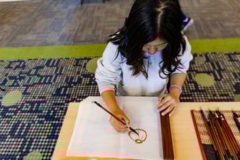 Girl in Chinese class practices drawing vocabulary in Chinese