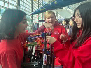 Two girls and one boy look at their VEX Robot