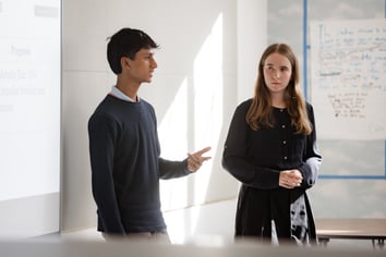 male and female friends academy students presenting at the front of a classroom