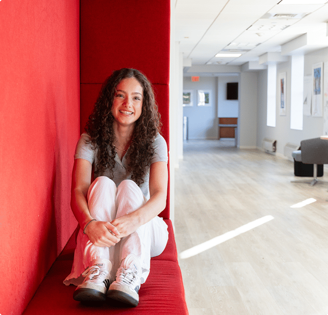 Teen girl sitting on a red bench in a hallway