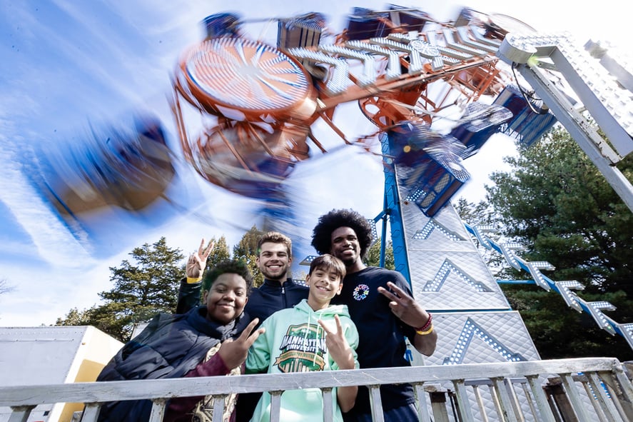 Four boys in front of Fall Fair rides