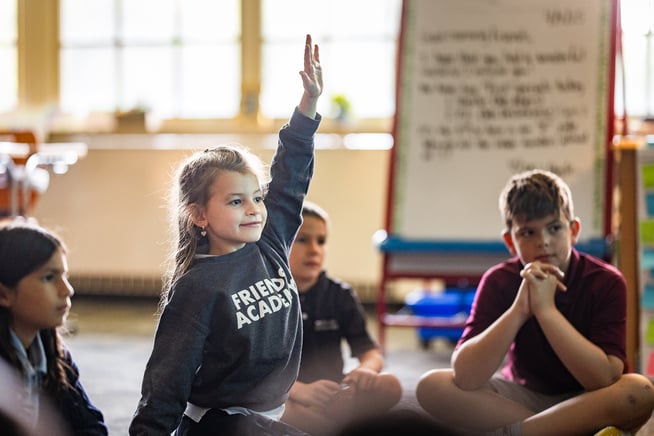 student raising hand with grey sweatshirt