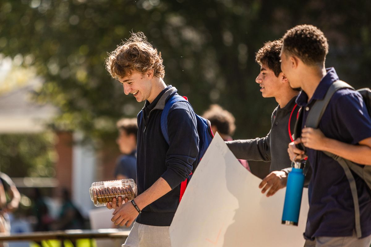 Three boys walking across campus toward club fair