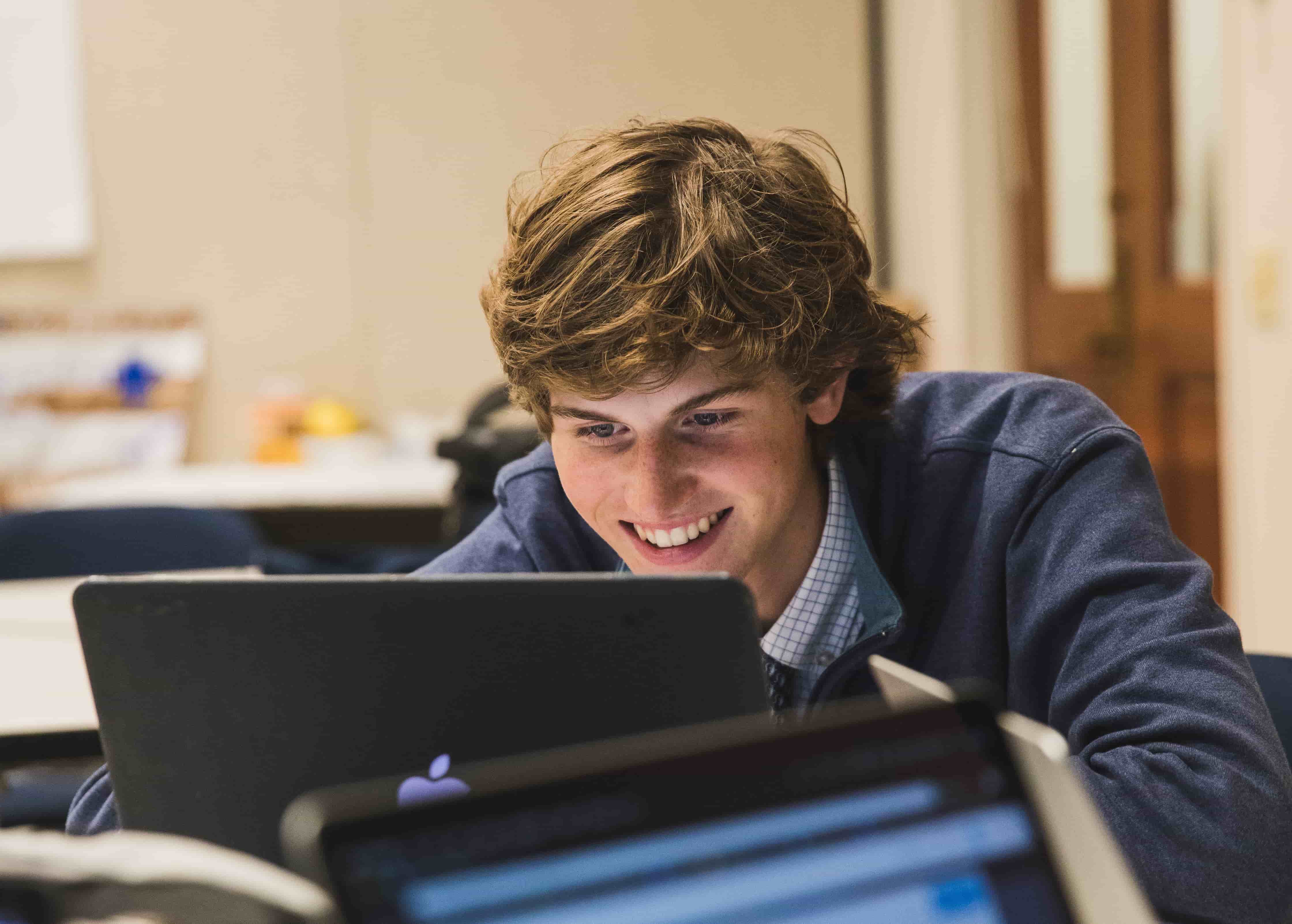 student smiling and doing work on laptop
